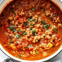 Hearty soup with meat, tomatoes, and herbs in a pot