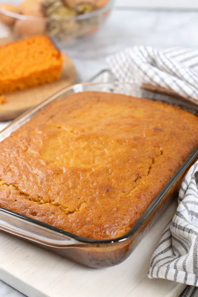 Freshly baked sweet potato cornbread in a glass baking dish on white wooden surface